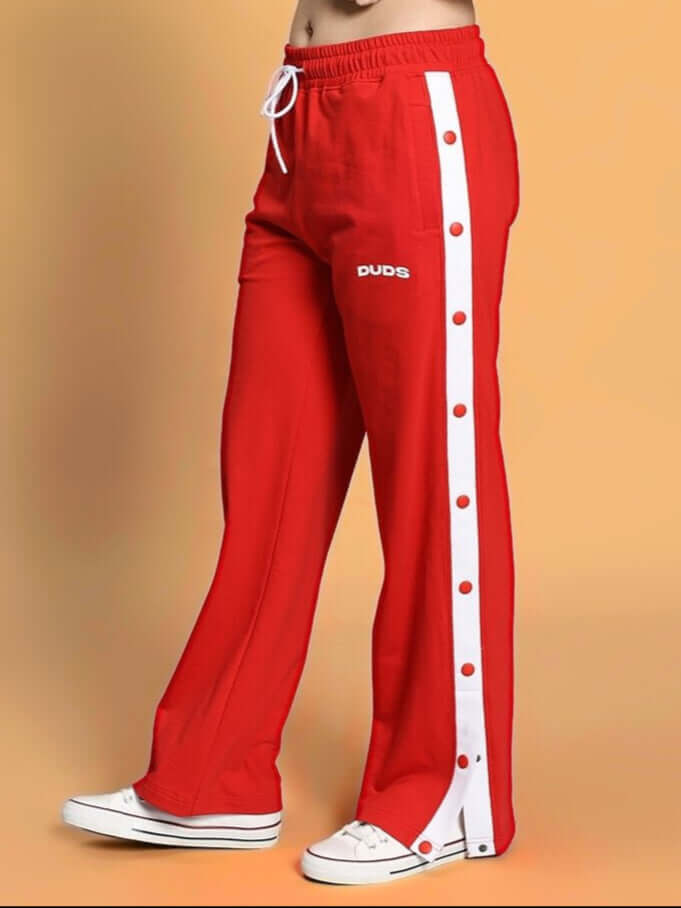 Women's red EZEL relaxed fit jogger by DUDS, featuring white side stripe with buttons, paired with casual shoes.