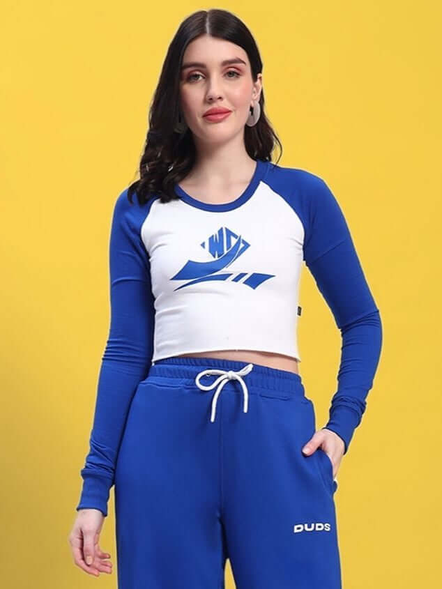Woman wearing white and blue long-sleeve EZEL top paired with matching blue pants, set against a yellow background.