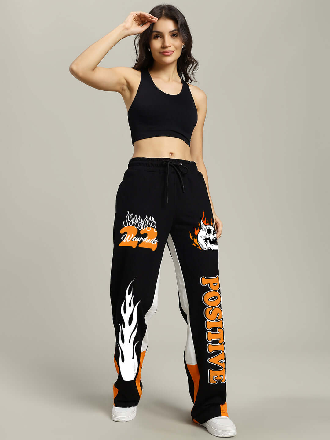 Woman wearing WOMENS FEARLESS CONTRAST RELAXED FIT JOGGERS BLACK-ORANGE with bold orange side details and positive graphic.