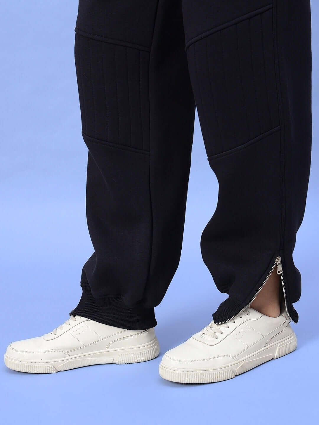 Navy blue women's fleece joggers with zipper detail, paired with white sneakers on a blue background.