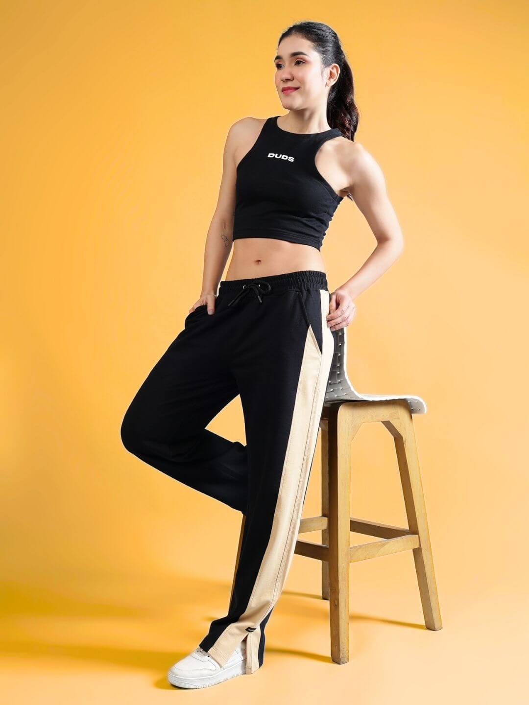 Model wearing Women's Fitfinity Co-ord Set in black with relaxed fit joggers and elastic waistband, posed against a warm background.
