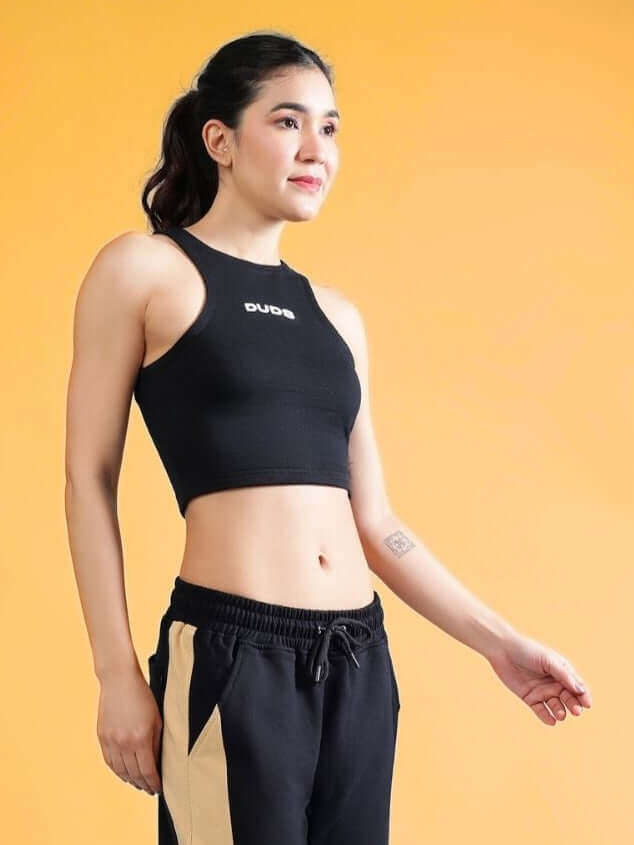 Women's Fitfinity Crop Top in black made of premium cotton French Terry Lycra blend, showcased on a model against an orange background.