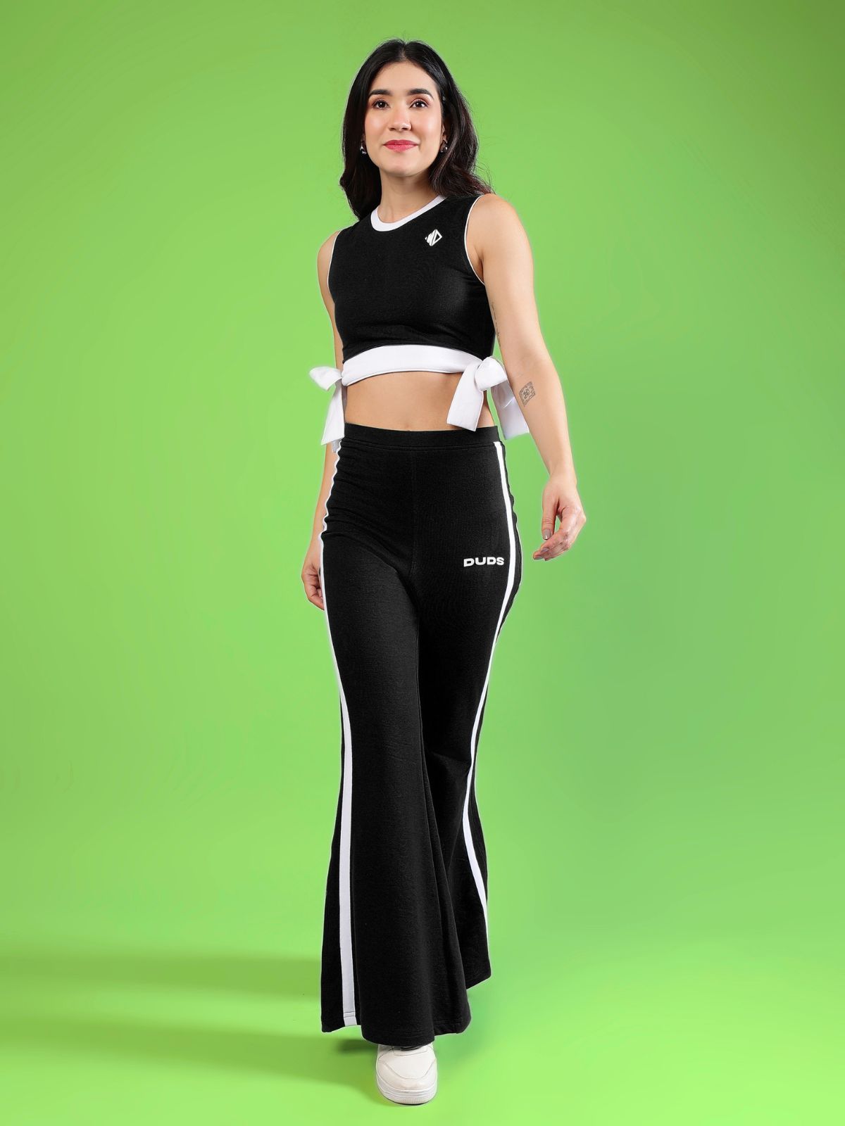 WOMENS FITTONIA COOL CO-ORD SET BLACK worn by a model against a vibrant green background, showcasing a stylish coordinated outfit.
