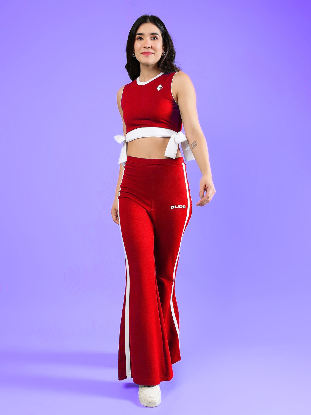 WOMENS FITTONIA COOL CO-ORD SET RED worn by a model, showcasing a stylish red two-piece outfit against a vibrant purple background.