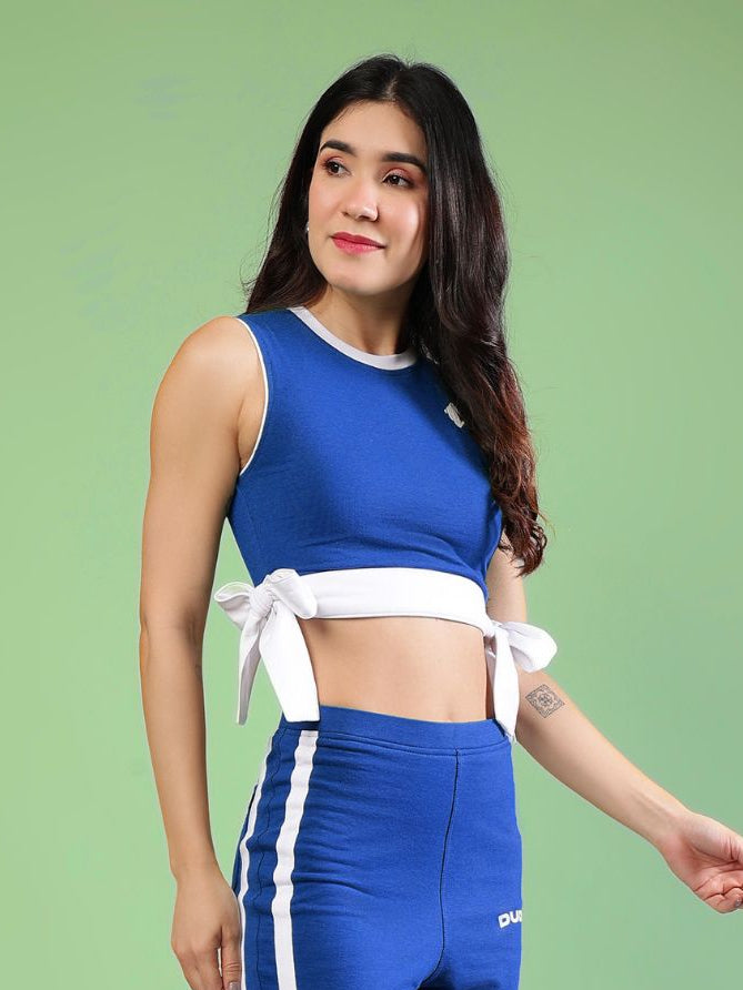 WOMENS FITTONIA COOL CROP TOP BLUE model wearing sporty blue crop top with white ties, perfect for casual wear and workouts.
