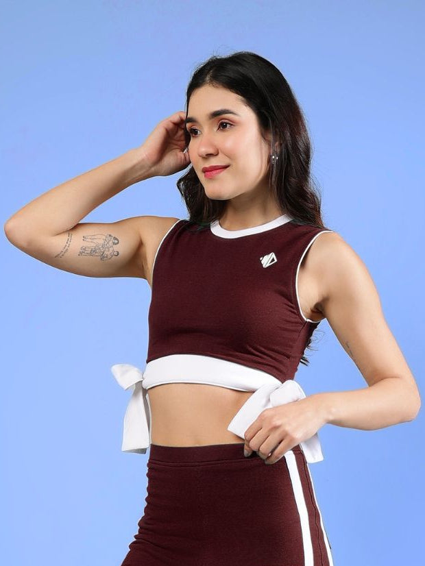 WOMENS FITTONIA COOL CROP TOP MAROON displayed on a model against a blue background, showcasing stylish design and comfort.