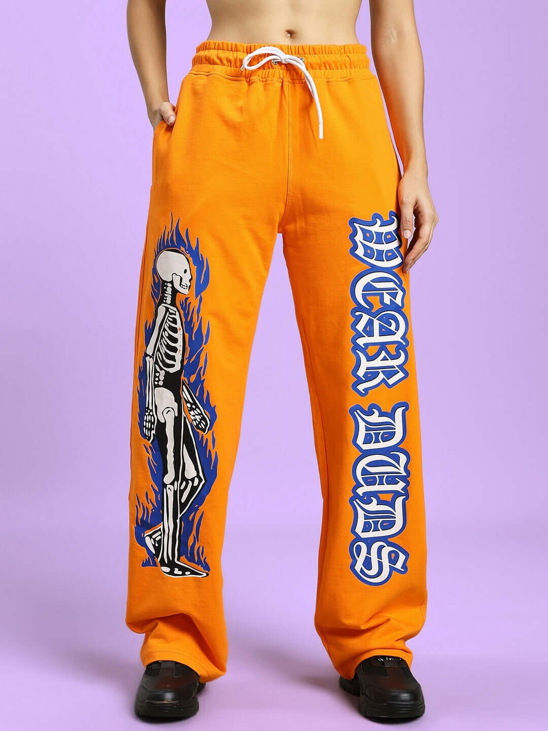 Orange relaxed fit joggers with flaming skeleton print and bold lettering, designed for women, made by DUDS.