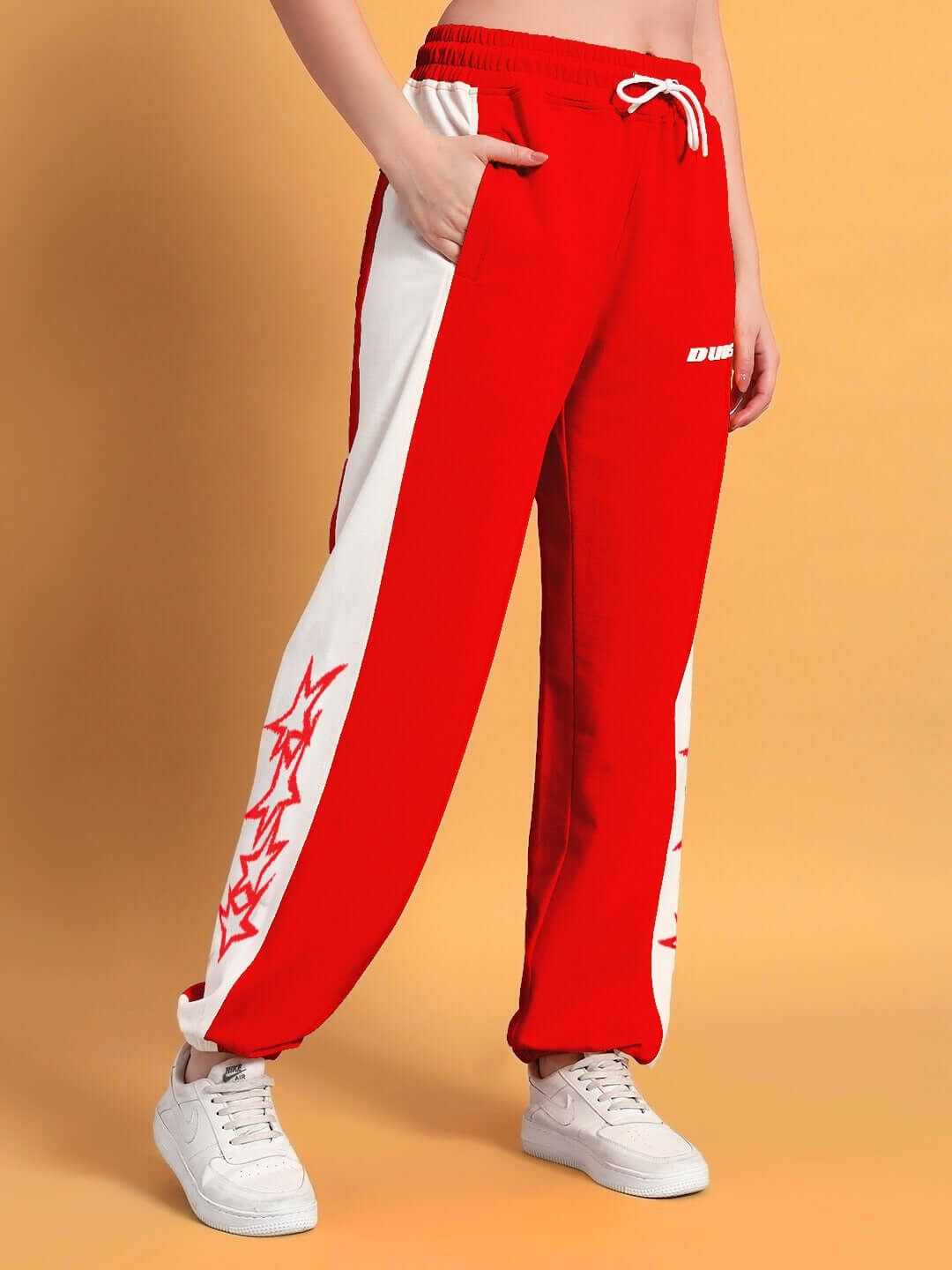 Women's red and white relaxed fit joggers by DUDS, featuring side pockets and drawstring, styled casually with white sneakers.