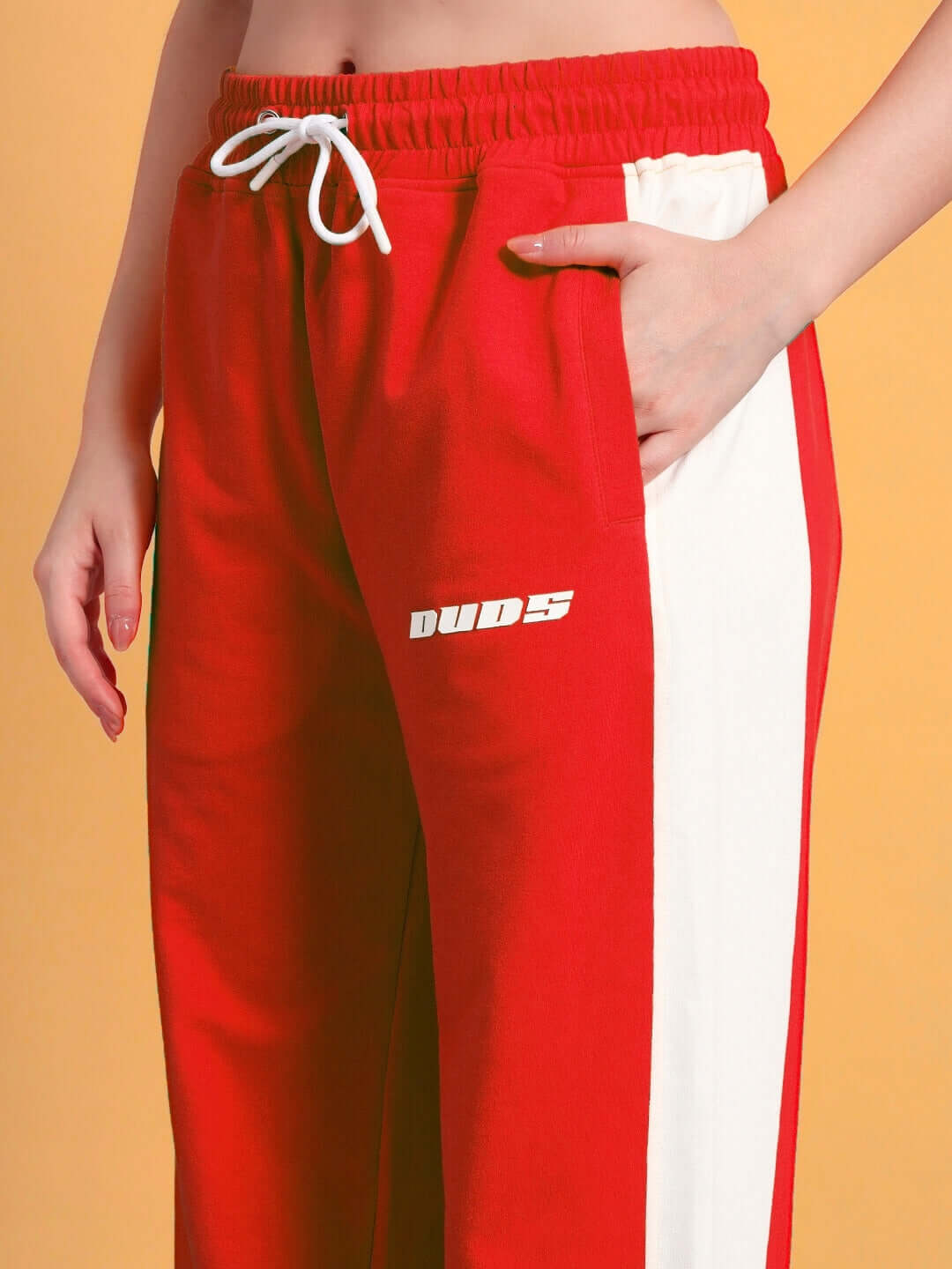 Close-up of women's red-white relaxed fit joggers by DUDS, featuring comfortable waistband and side stripe detail.