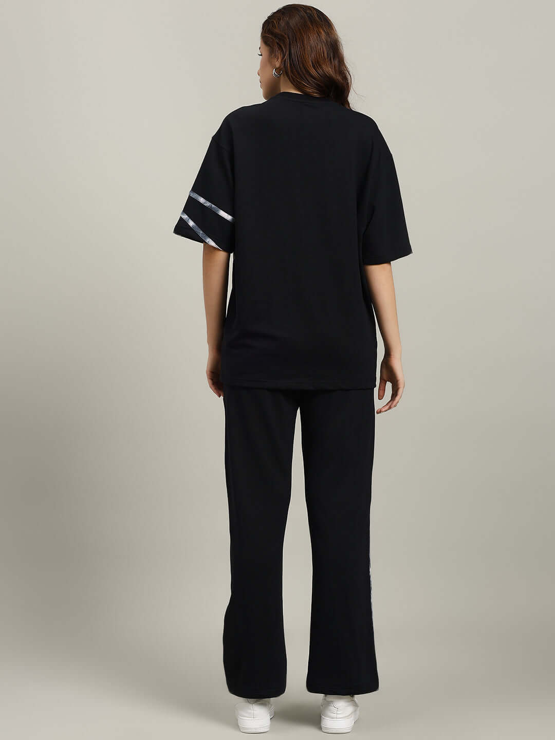 Woman wearing WOMEN'S FLICKER OVERSIZED CO-ORD SET BLACK, featuring relaxed fit joggers with elasticated waistband and drawstring.