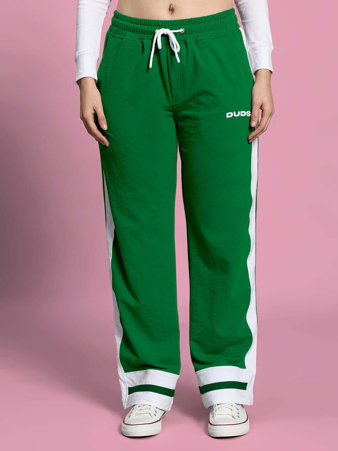 Model wearing green pants from WOMEN'S FLORA CO-ORD SET PINK GREEN by WEAR DUDS, styled with white sneakers against a pink backdrop.