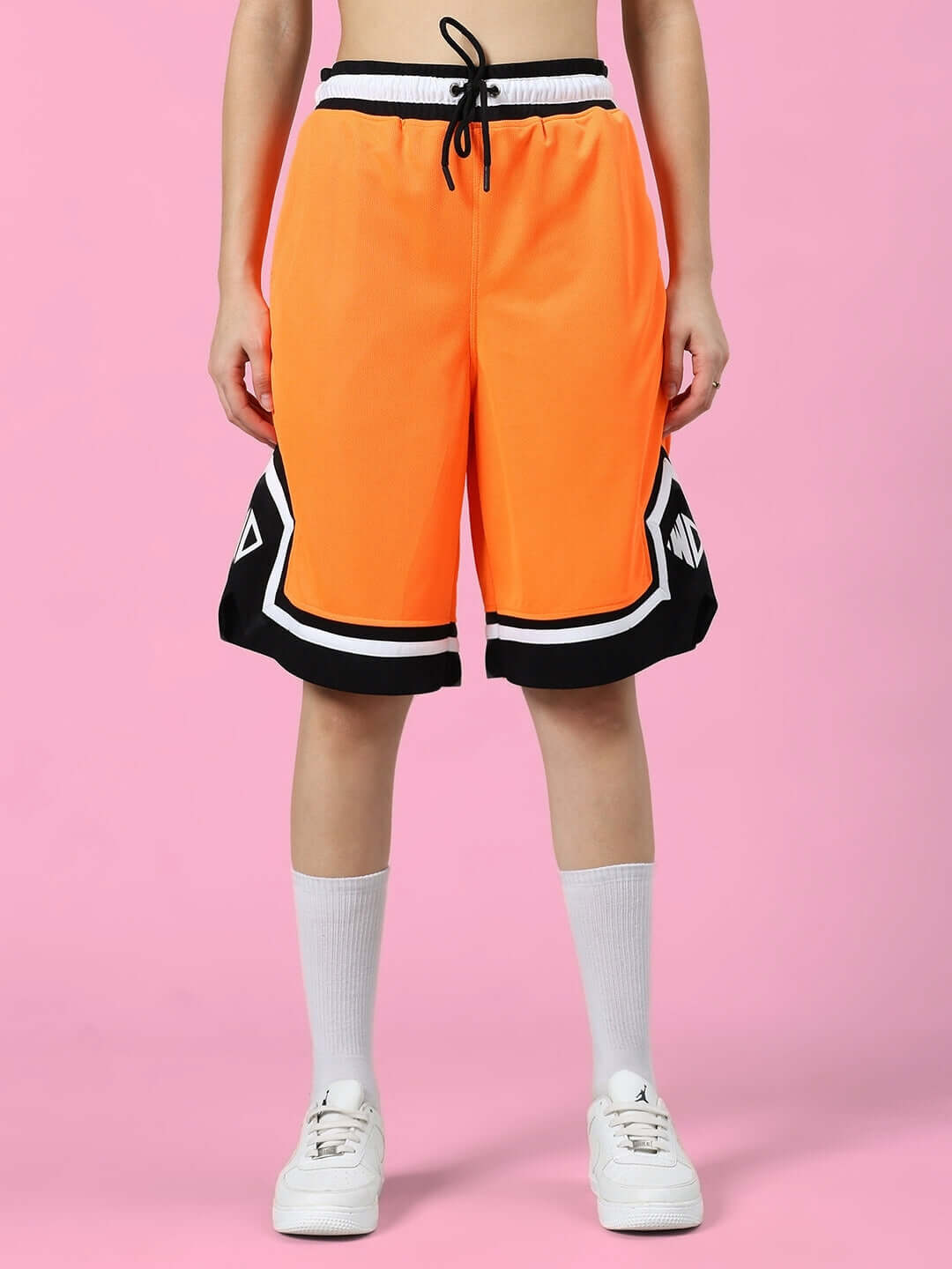 Model wearing WOMEN'S FRANKY GYM CO-ORD SET ORANGE BLACK, featuring orange shorts with black and white accents. Sports polyester fabric.