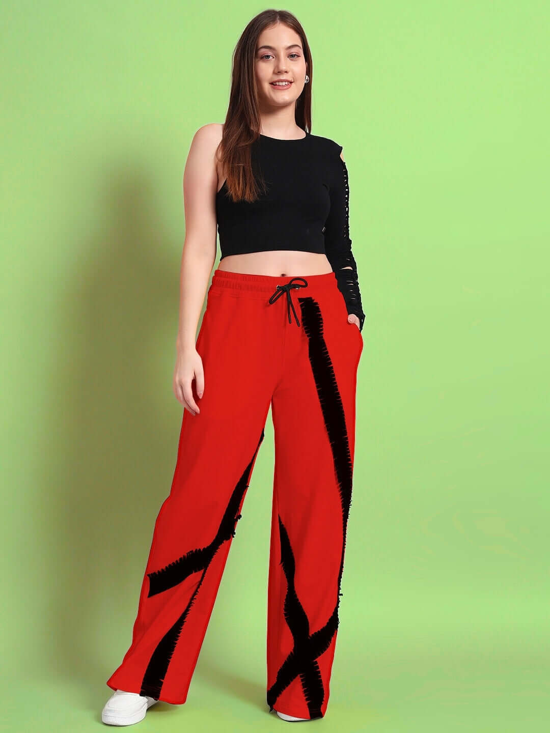 Woman wearing red frayed textured stripes joggers from DUDS, standing against a green background.