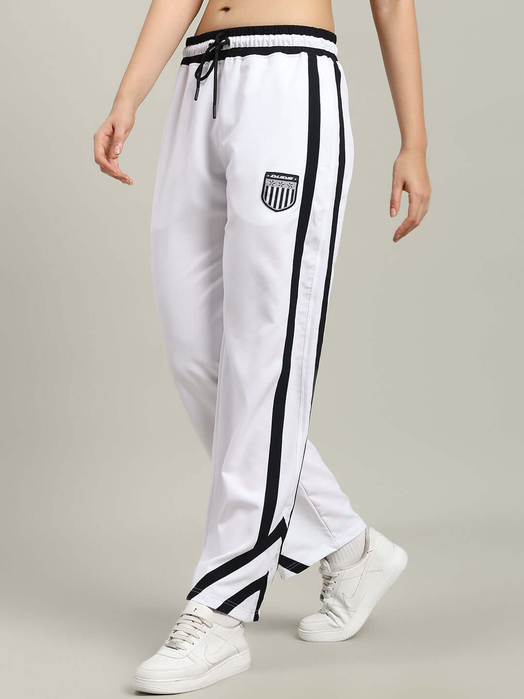 Woman wearing WOMEN'S FRIZZLE RELAXED FIT JOGGER WHITE with black stripes, standing in stylish casual attire.