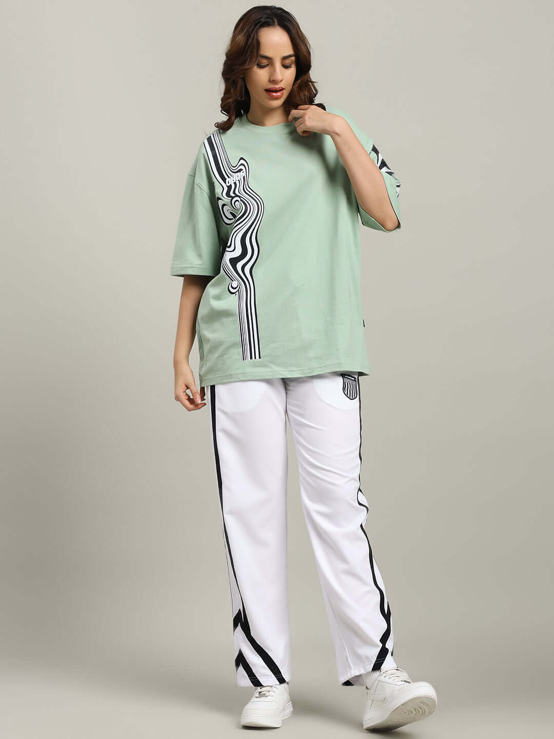 Woman wearing WOMEN'S FRIZZLE RELAXED FIT JOGGER WHITE with casual green top, standing in neutral background.
