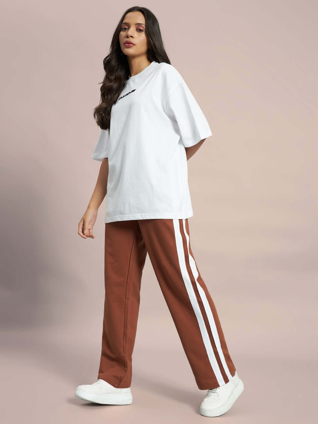 Woman wearing brown joggers with white stripes, paired with a white t-shirt, emphasizing casual style and comfort.