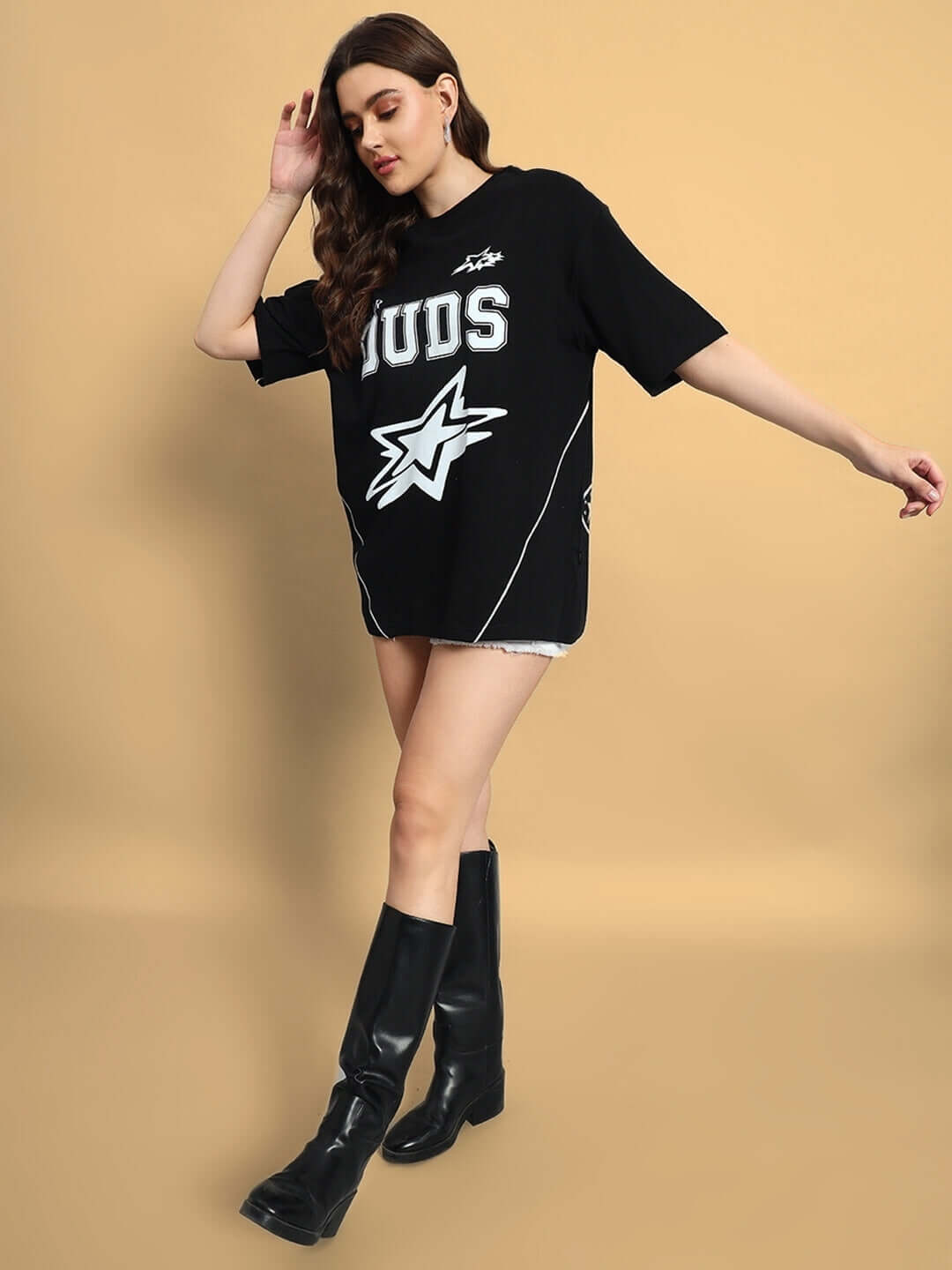 Woman wearing oversized black galaxy t-shirt with custom fit option, styled with black boots, ideal for a casual, trendy look.