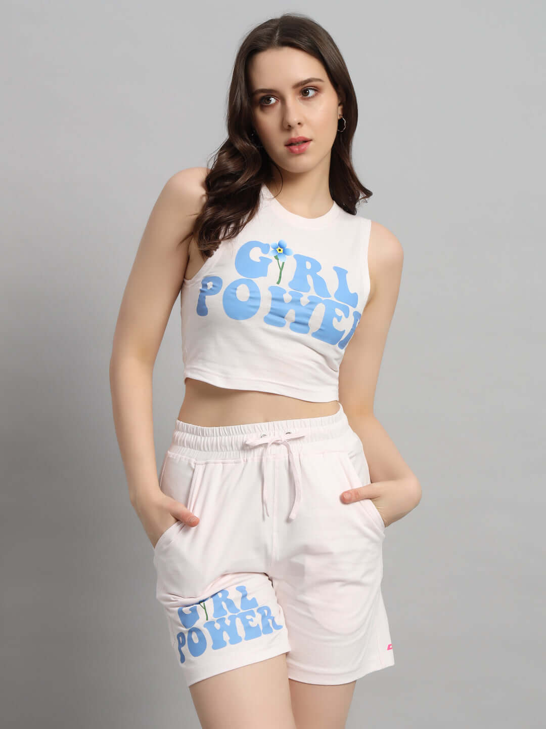Woman wearing baby pink co-ord set with 'Girl Power' print, featuring sleeveless top and shorts. Fashionable and empowering outfit.