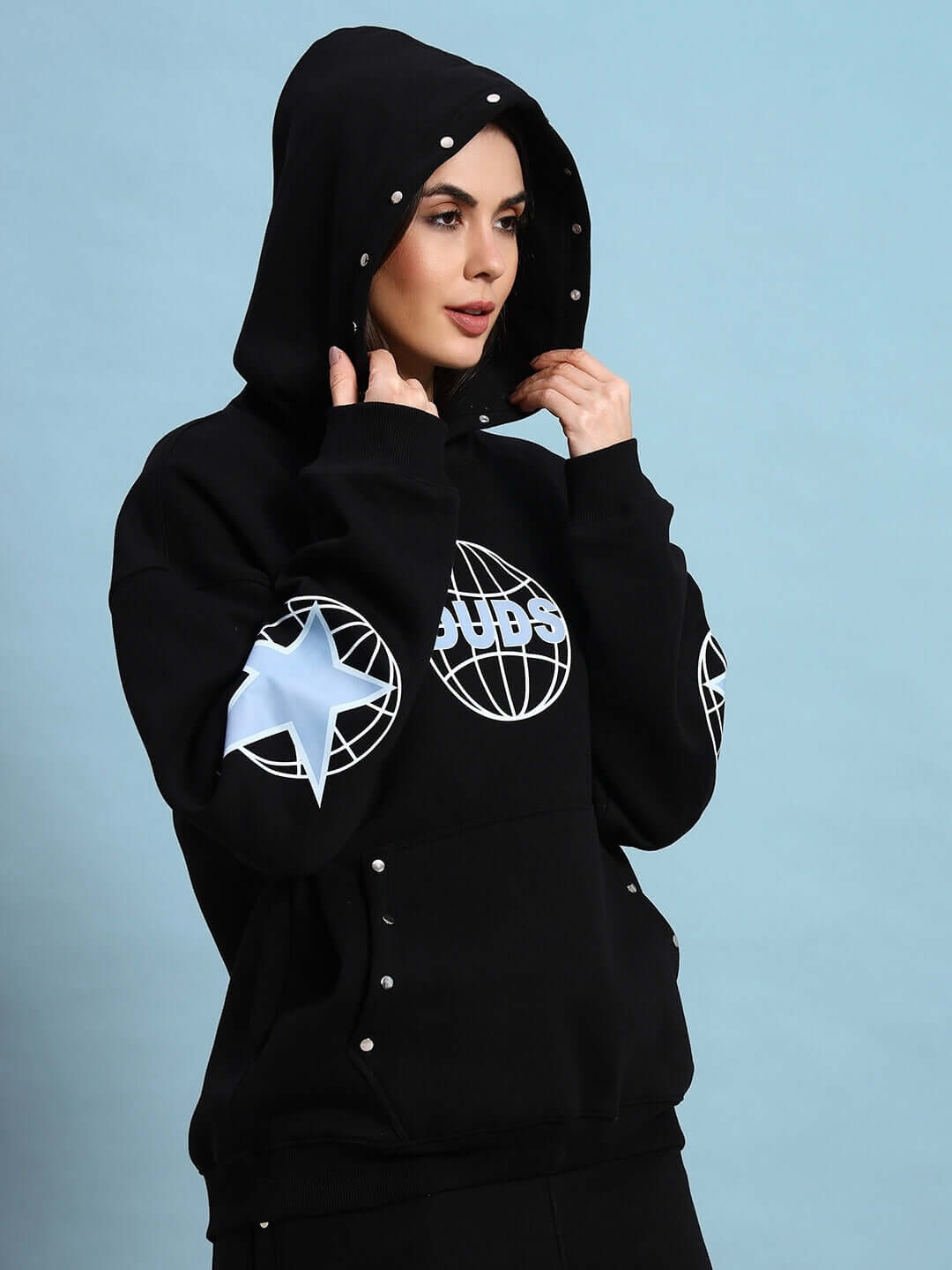 Woman wearing Women Global Fleece Hoodie Black with hood up, featuring global and star graphic designs, perfect for streetwear fashion.