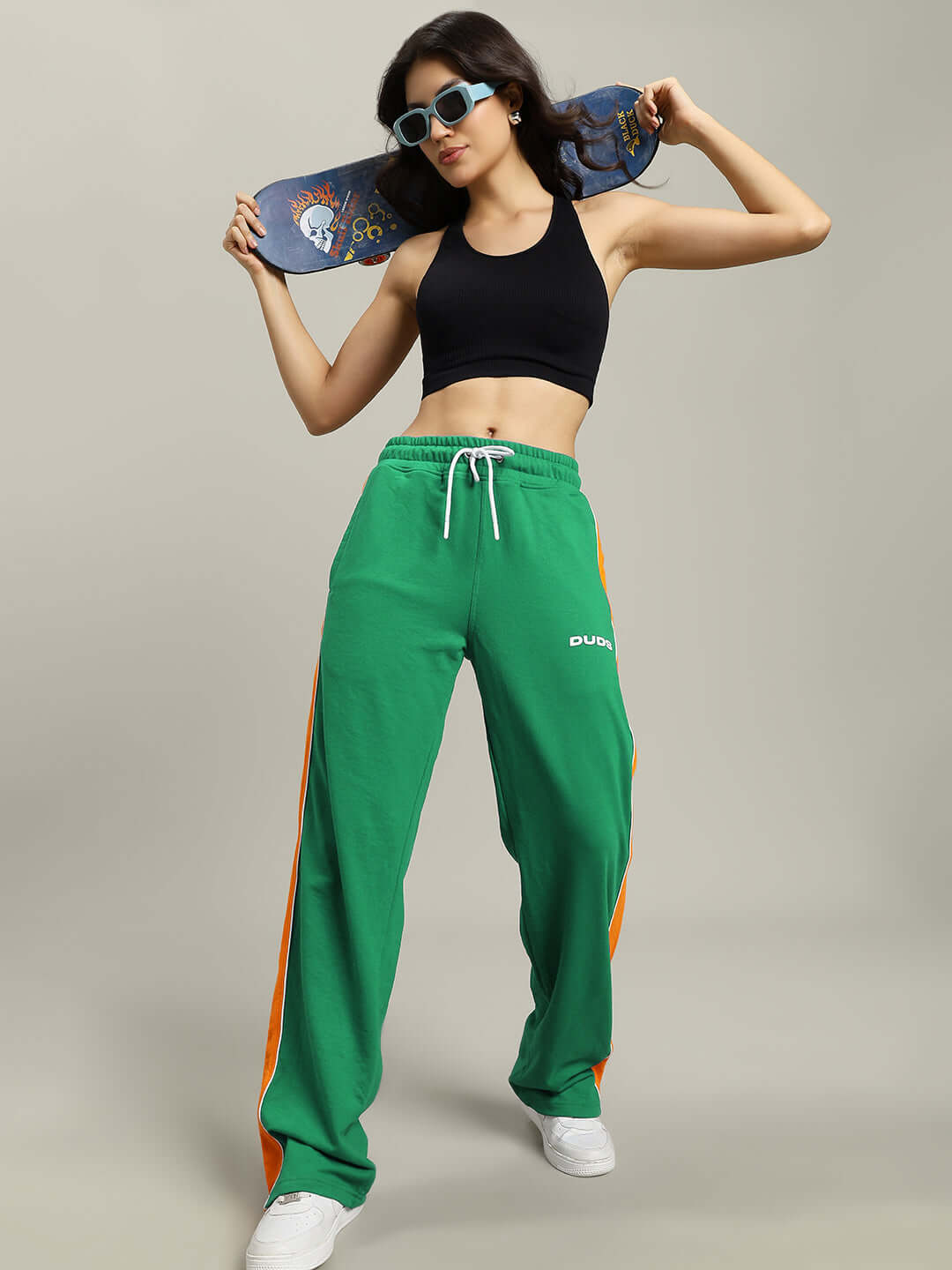 Model wearing Women's Sanford Stripe Joggers in green with skateboard, highlighting sporty style and comfort by DUDS.