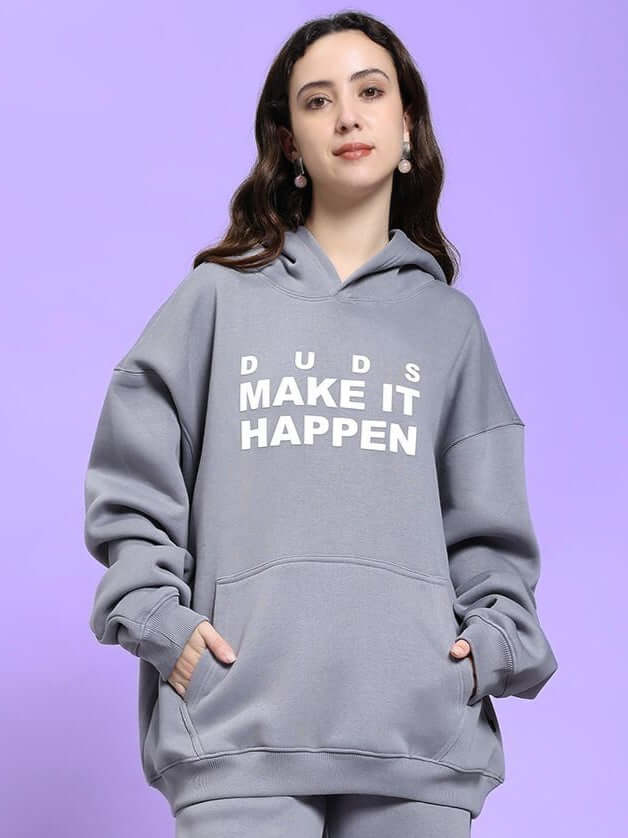 WOMEN'S MAKE IT HAPPEN FLEECE HOODIE GREY, modeled by a woman against a purple background.