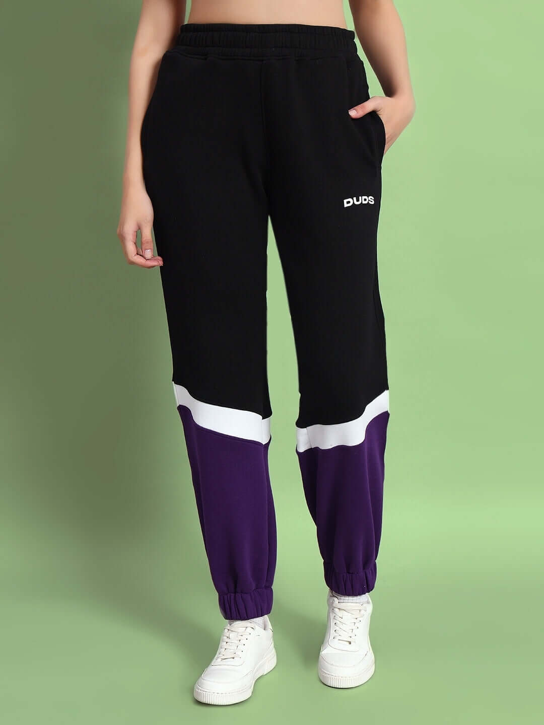 Woman wearing WOMEN HARLEY FLEECE COLORBLOCK CO-ORD WHITE PURPLE joggers with colorblock design, showcasing sporty style.