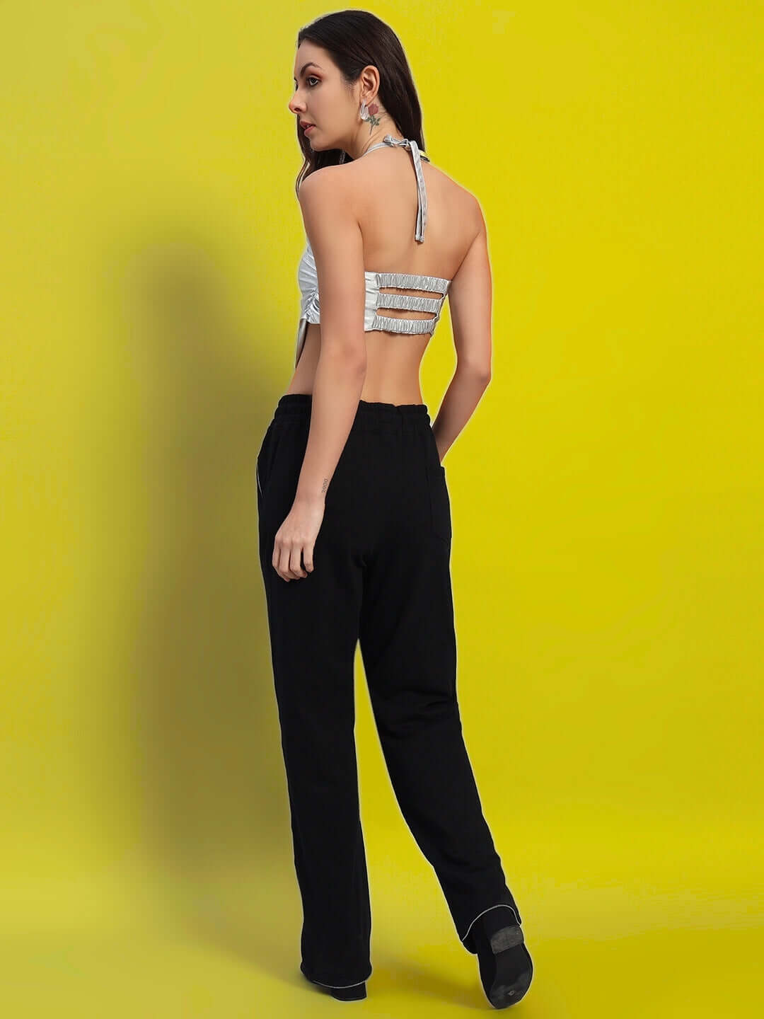 Woman wearing black Harper relaxed fit jogger, back view, against a yellow background.