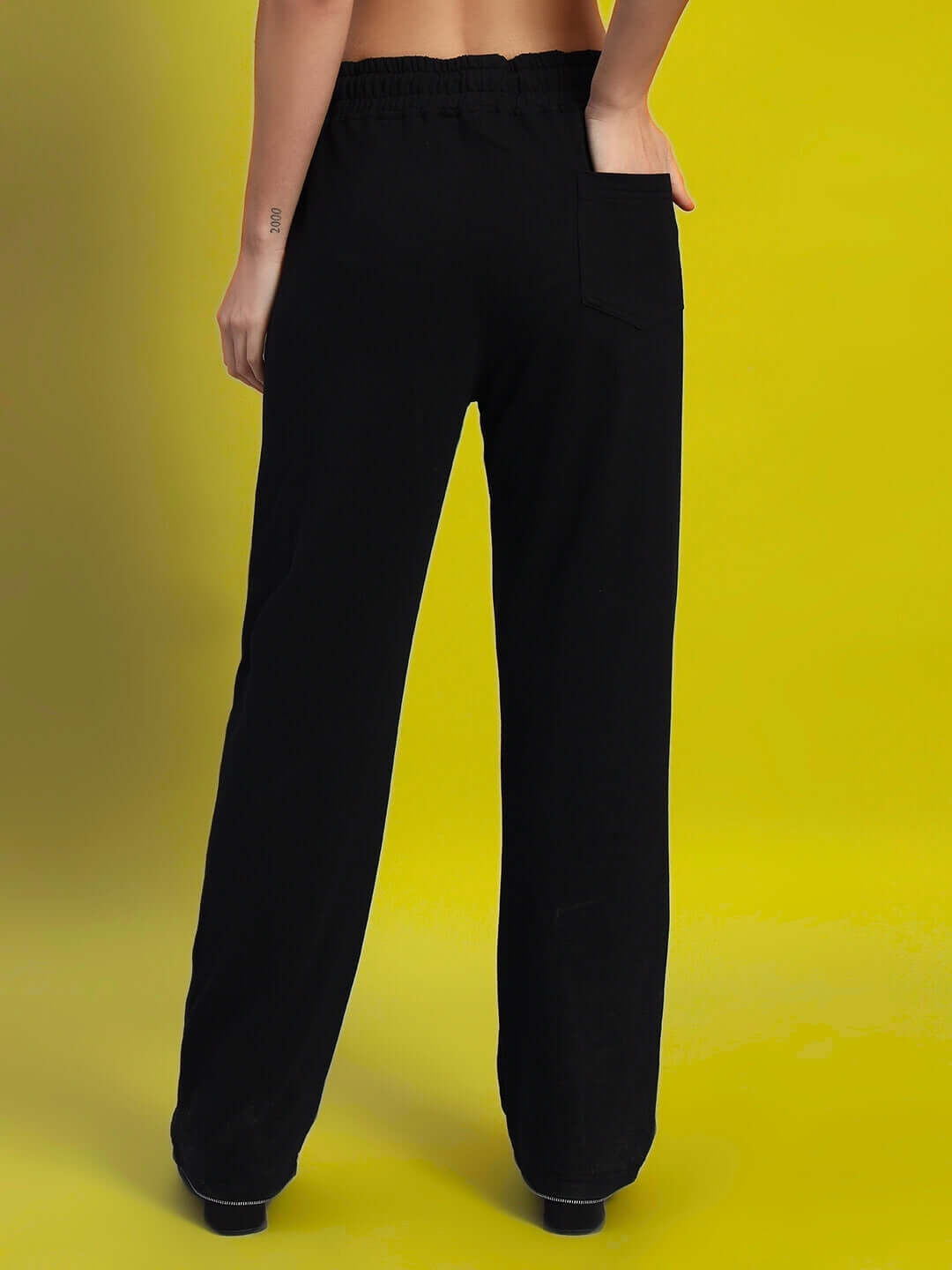 Back view of Women's Harper Relaxed Fit Jogger in black, showcasing comfortable and stylish design on a yellow background.