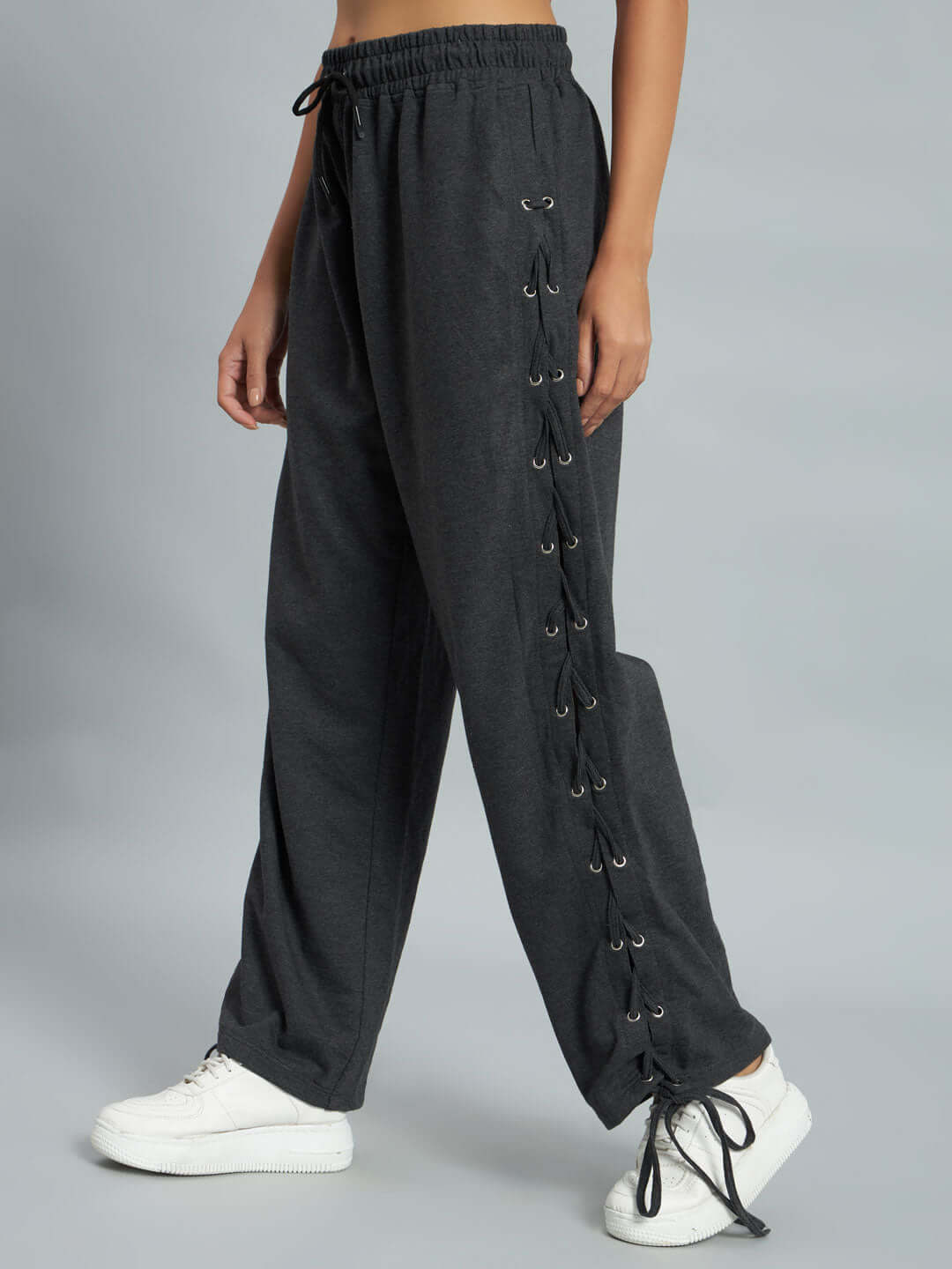 Model wearing Women's Hazel Relaxed Fit Joggers in grey with lace-up side detail, paired with white sneakers.