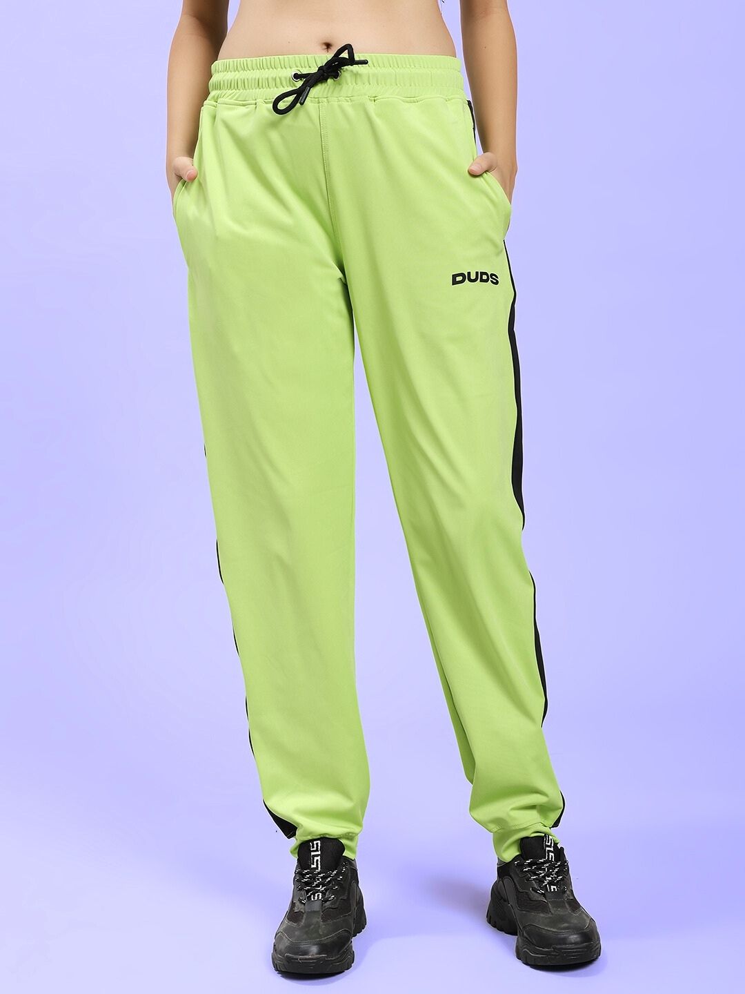 Model wearing WOMEN HIGH PERFORMANCE CO-ORD SET NEON GREEN with sporty joggers and black shoes, showcasing trendy sports fashion.