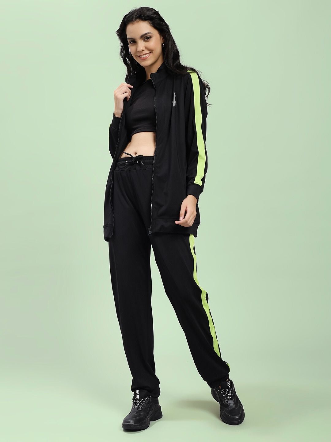 Woman modeling WOMEN HIGH PERFORMANCE JACKET IN BLACK with lime green accents, perfect for outdoor activities and city commutes.