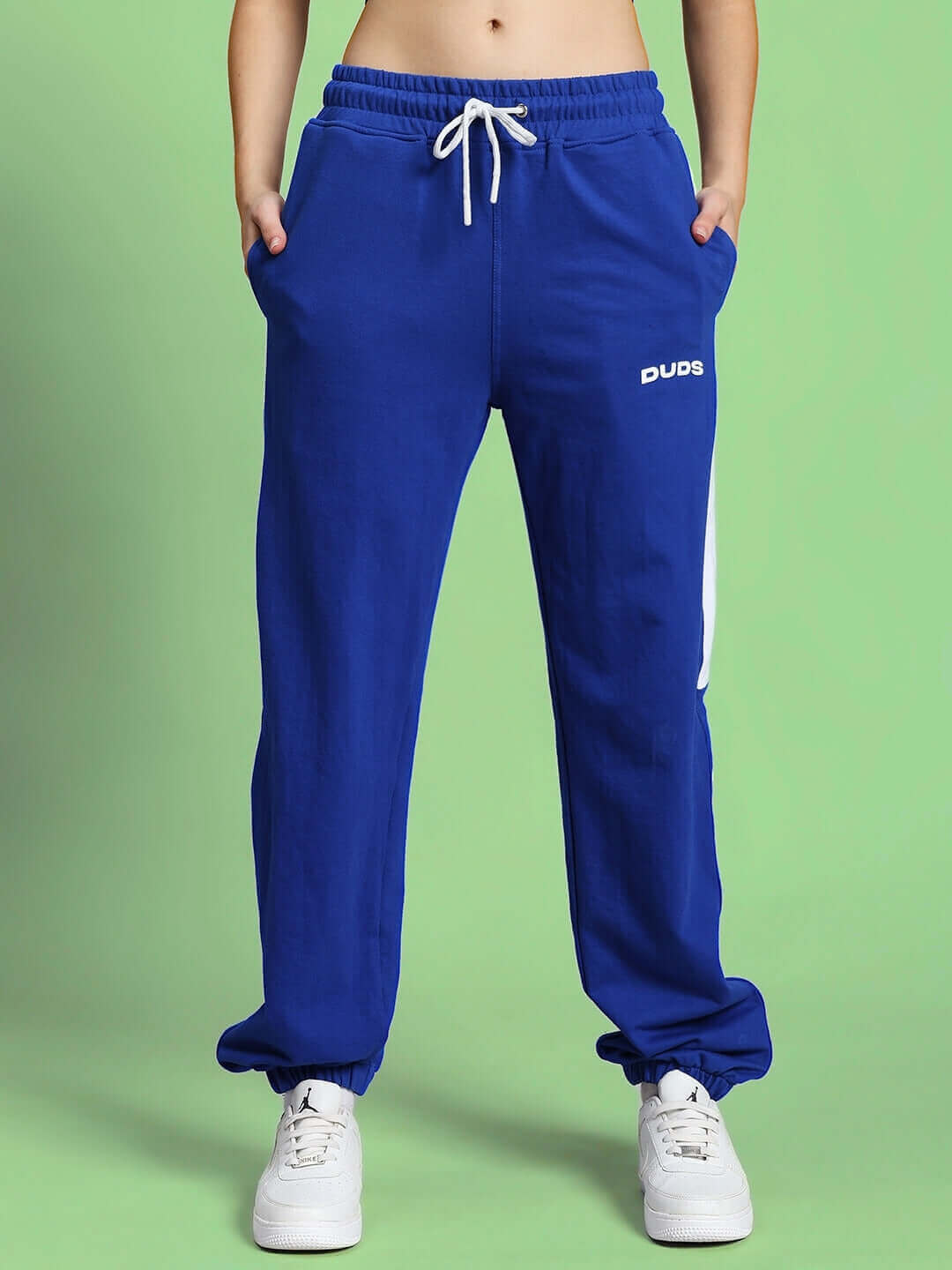 Woman wearing blue DUDS joggers with contrast design, made-to-order fashion with custom fit available, front view.