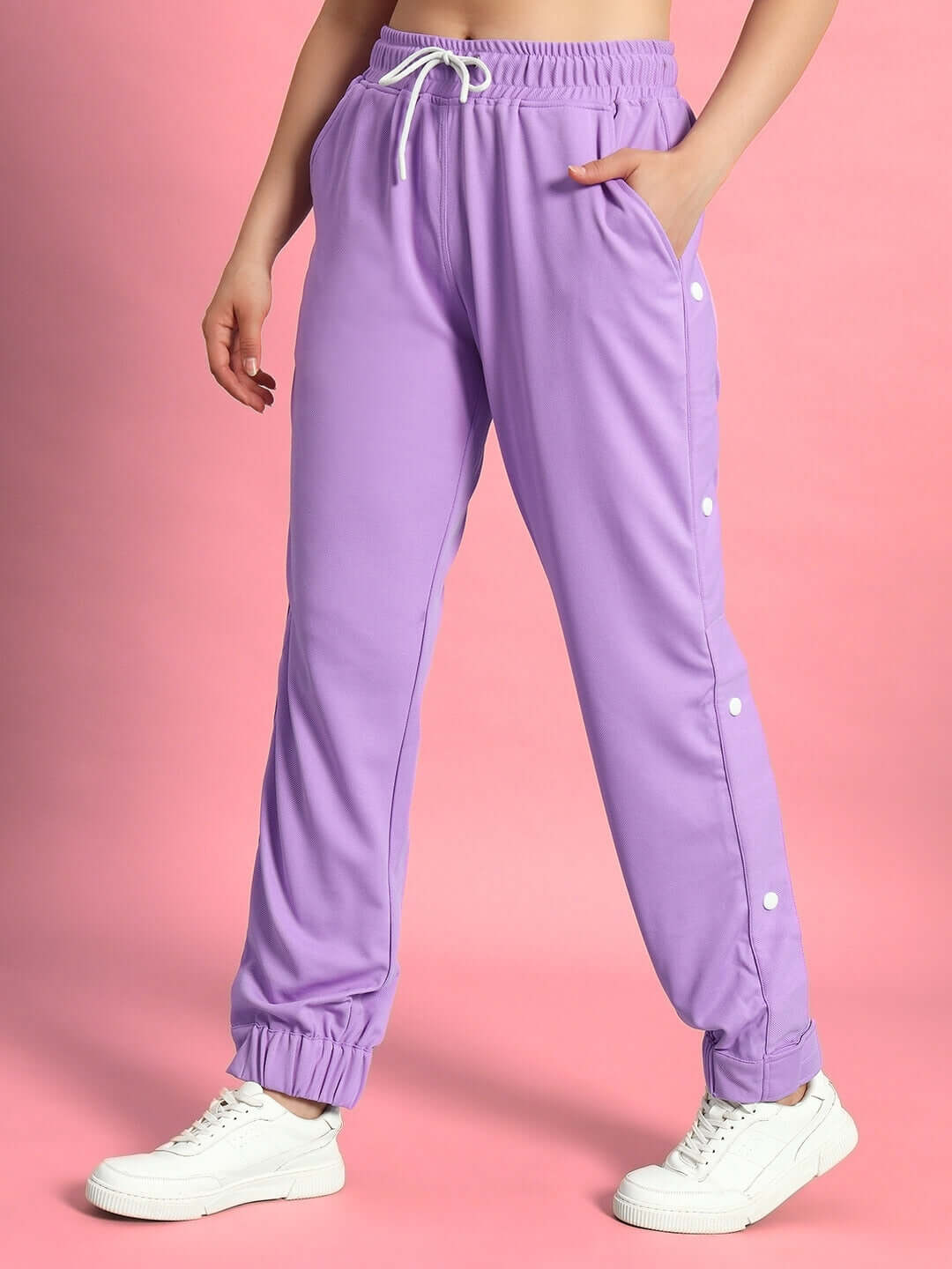 Lavender women's hip hop joggers with drawstring waist and button details, styled with white sneakers on a pink background.
