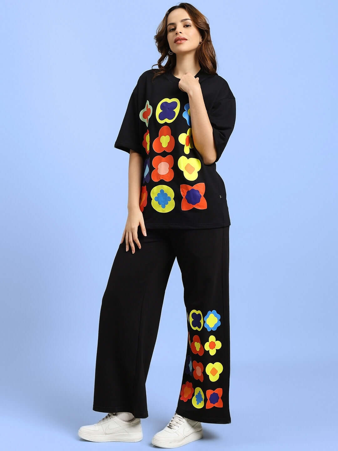 Woman wearing WOMEN'S HOLLISTER CO-ORD SET BLACK with colorful floral patterns, featuring an oversized t-shirt and matching joggers.