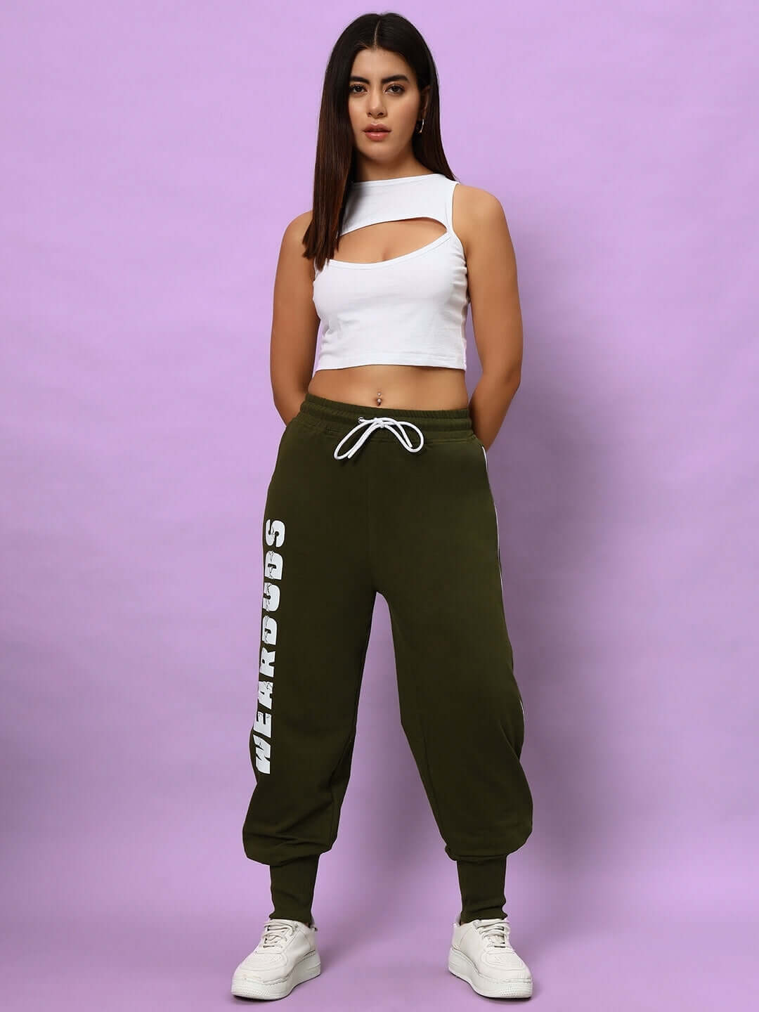 Model wearing Women's Hunter Joggers in olive green with drawstring, paired with a white crop top, standing against a lavender background.
