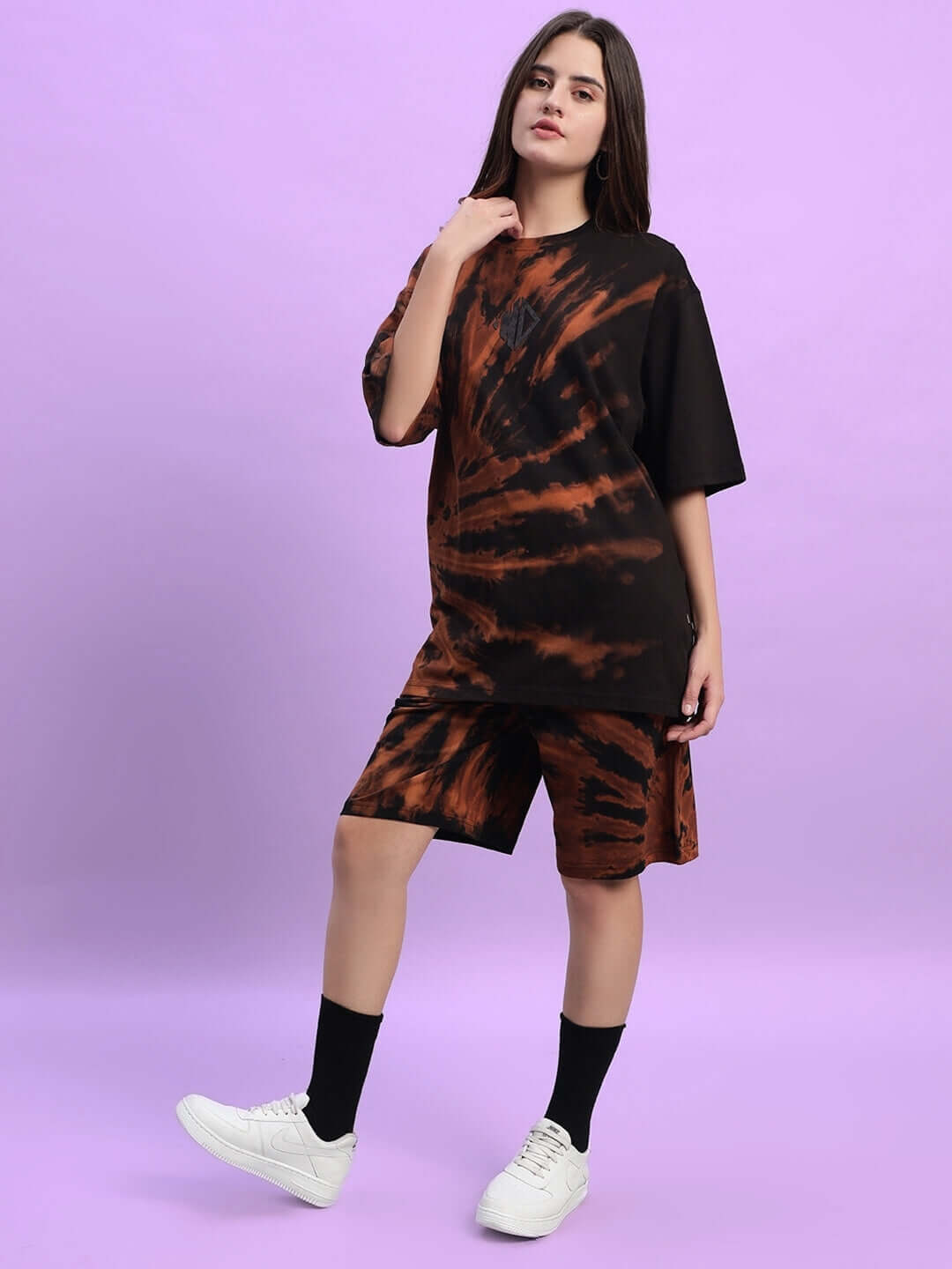 Woman wearing black tie-dye co-ord set, featuring premium cotton French terry fabric, styled with sneakers on a purple background.