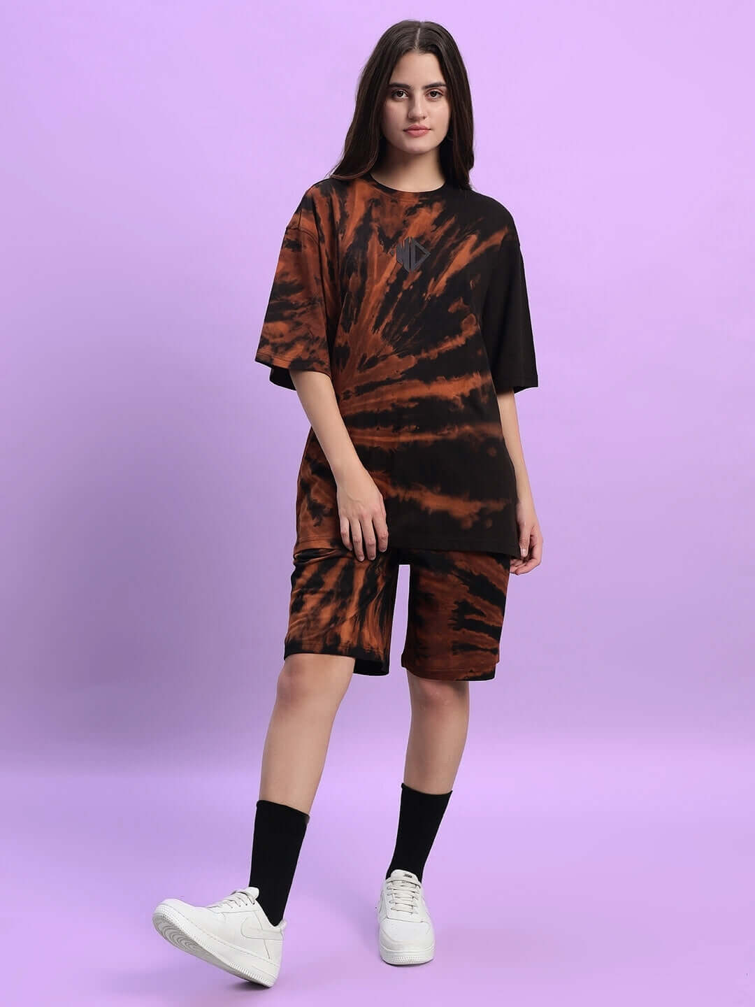 Model wearing women's black tie-dye co-ord set, cotton French terry lycra, styled with white sneakers. Fashionable casual wear.