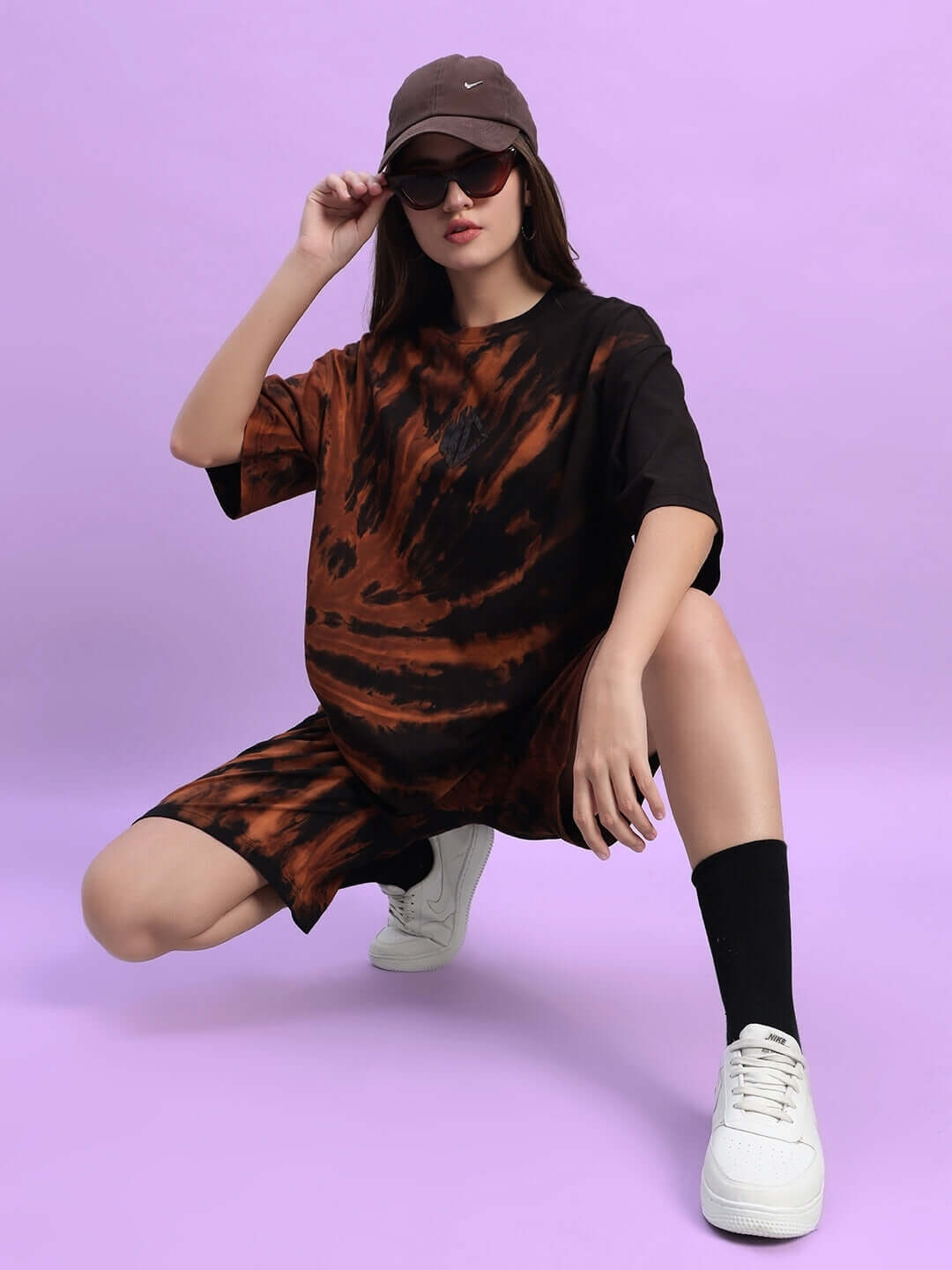 Model wearing Women's Hustler Tie-Dye Co-ord Set in black with shorts and oversized top, complete with white sneakers and a cap.