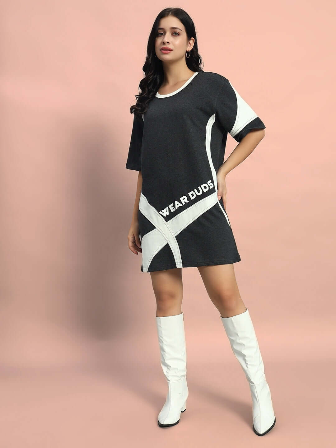 Elegant woman wearing a dark grey Women's Jackson Dress made of premium 100% cotton, styled with white boots, against a peach background.