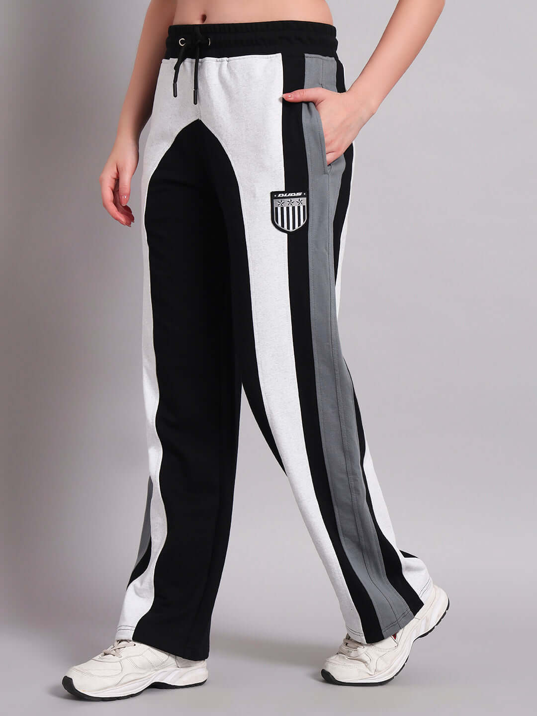 Woman wearing black and grey color block relaxed-fit joggers with a logo patch, showcasing a casual athletic look.