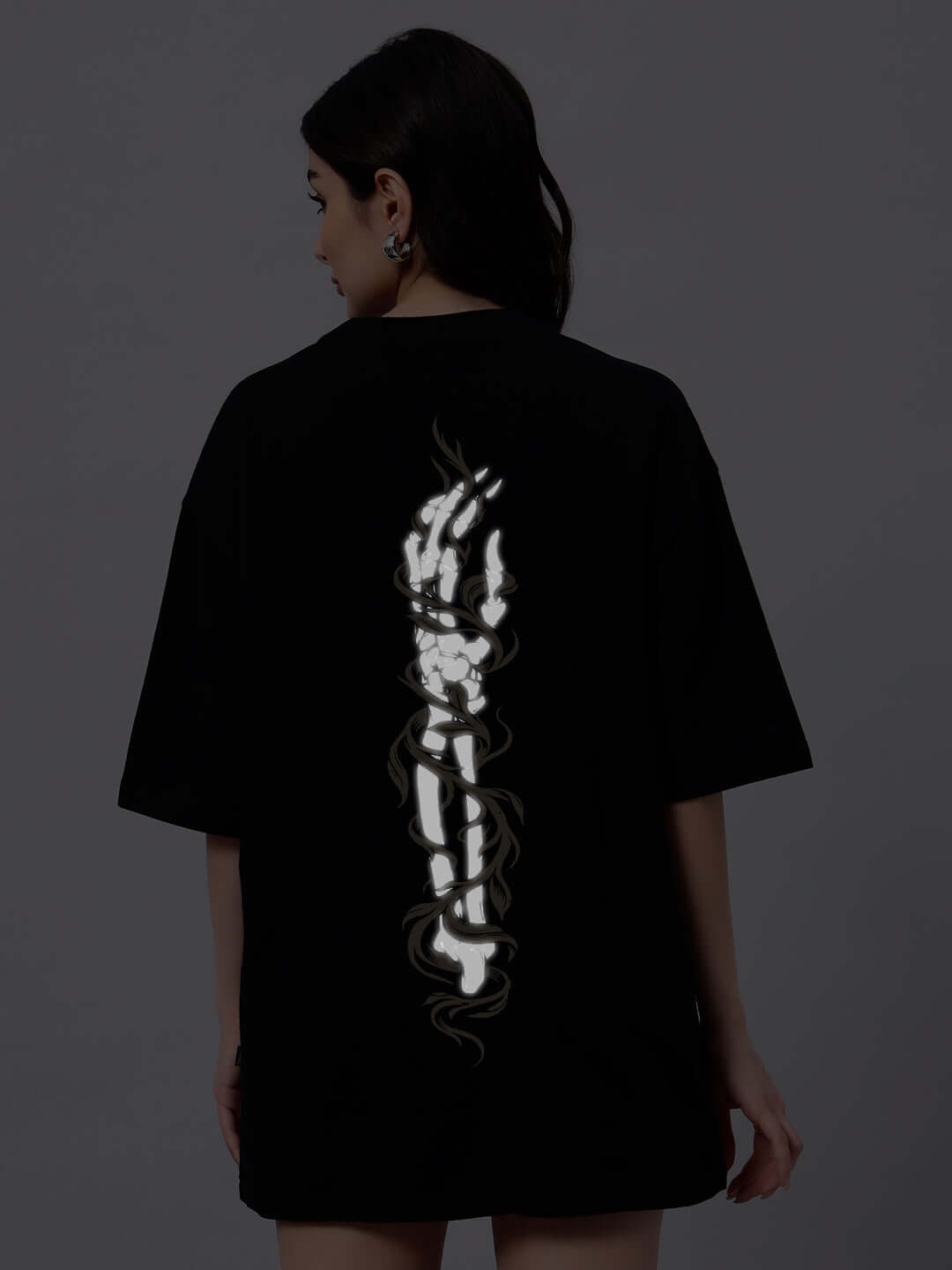 Back view of WOMEN'S JELVIN OVER-SIZED T-SHIRT in black with artistic design, made from premium cotton blend fabric, worn by female model.