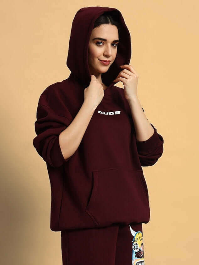 Model wearing women's wine fleece co-ord with hood up.