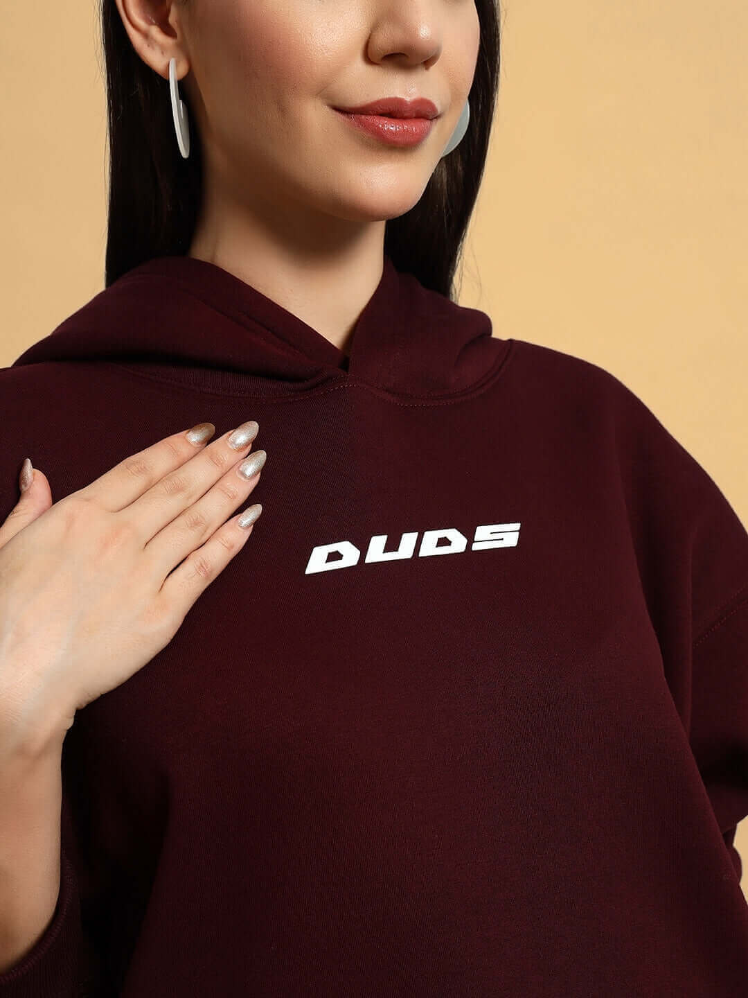 Close-up of woman in wine-colored fleece hoodie with logo, showcasing fashion-forward casual wear design.