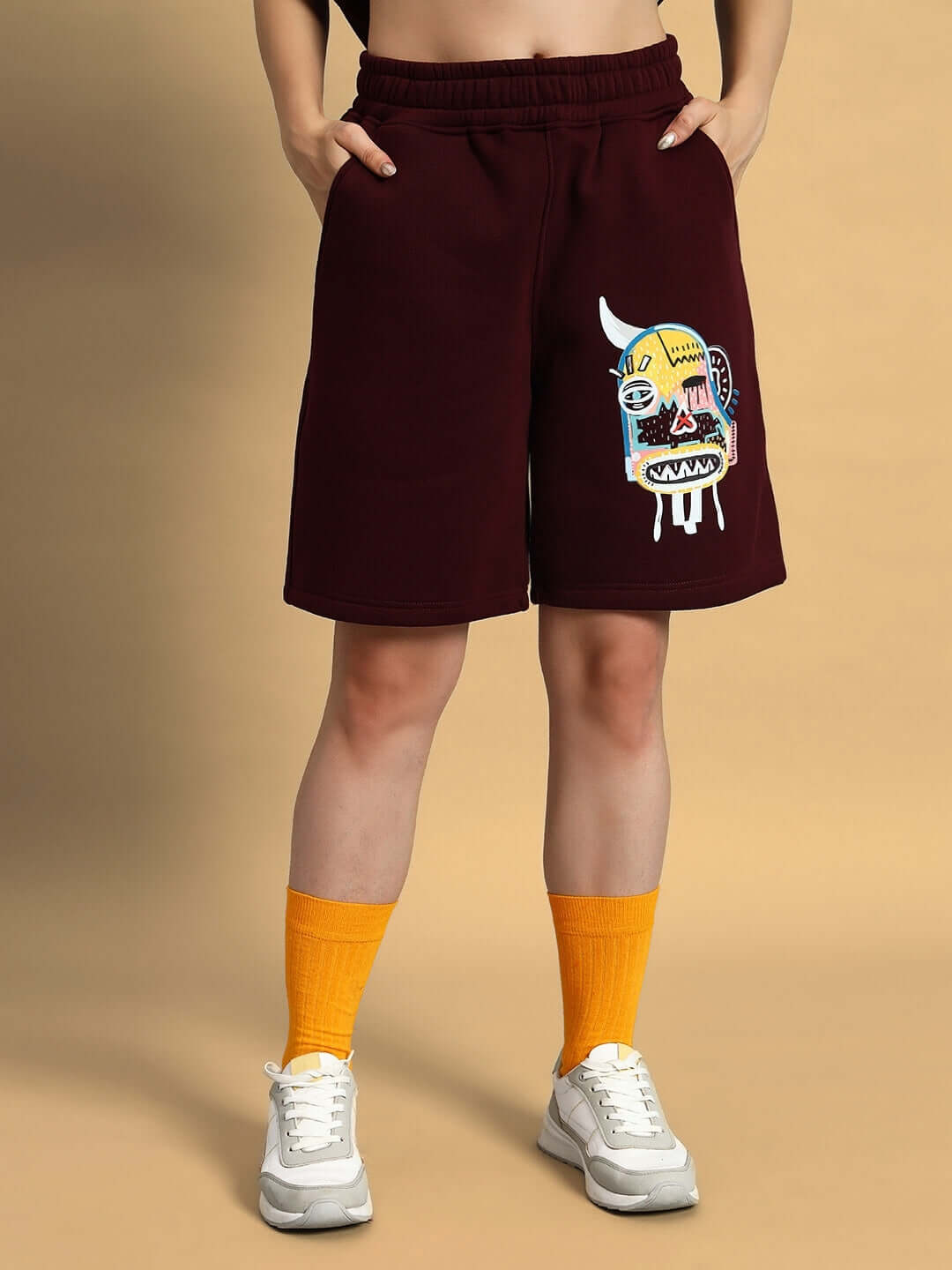 Model wearing WOMEN JUMBLED FLEECE SHORTS WINE with graphic design, from WEAR DUDS, styled with yellow socks and white sneakers.