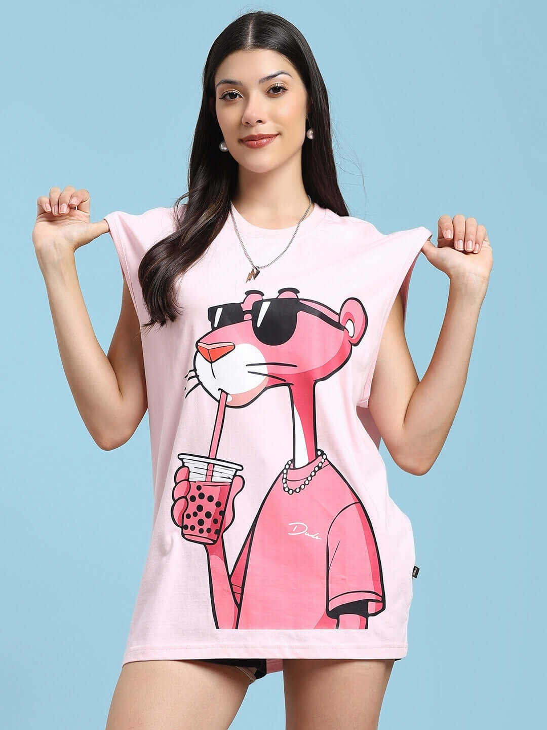 Woman wearing a pink t-shirt with Pink Panther print, holding bubble tea and smiling, light blue background