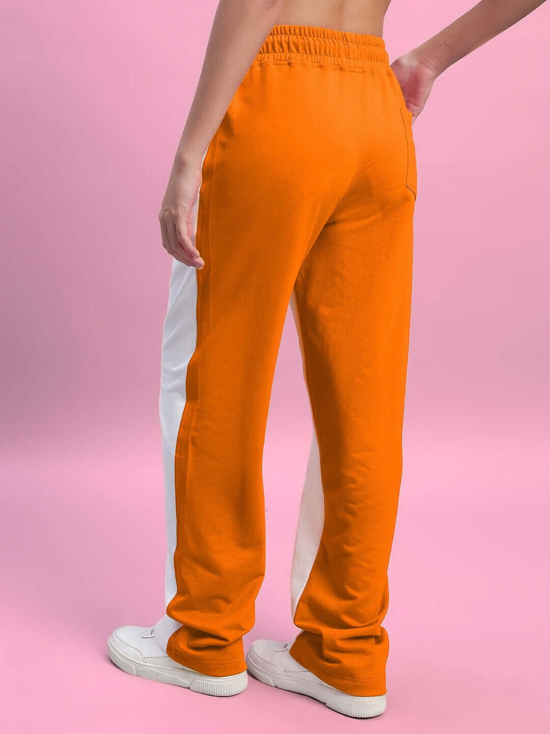 Back view of women's orange and white relaxed fit joggers, made to order by DUDS, displayed against a pink background.