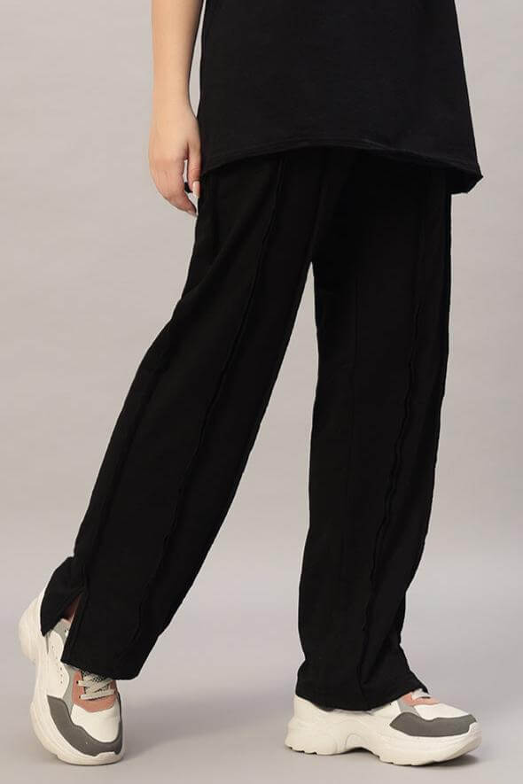 Black women's joggers with side slits, paired with white sneakers for a stylish look.