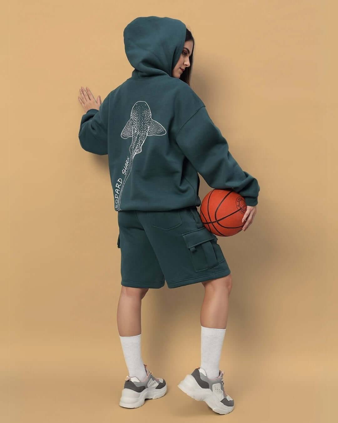 Woman wearing WOMENS LEOPARD SHARK FLEECE HOODIE TEAL GREEN, holding a basketball, showcasing stylish and cozy design.