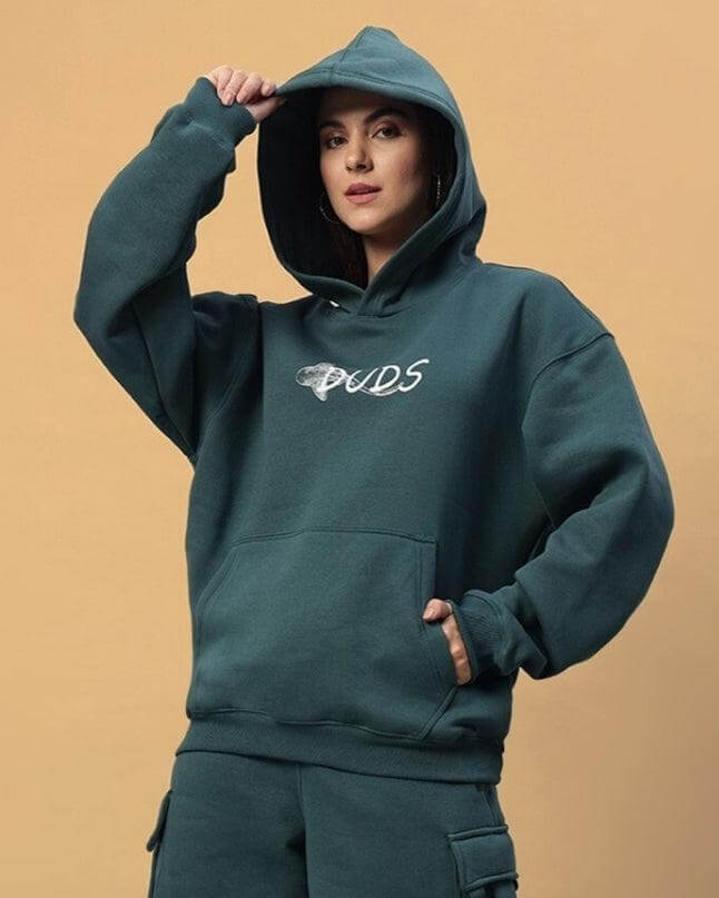 Woman wearing WOMENS LEOPARD SHARK FLEECE HOODIE TEAL GREEN, showcasing teal green fleece hoodie with logo design.