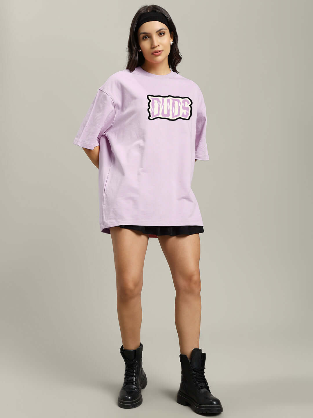 Model wearing a lavender oversized T-shirt with 'Let’s Get Spooky' design, paired with black boots, showcasing casual style.